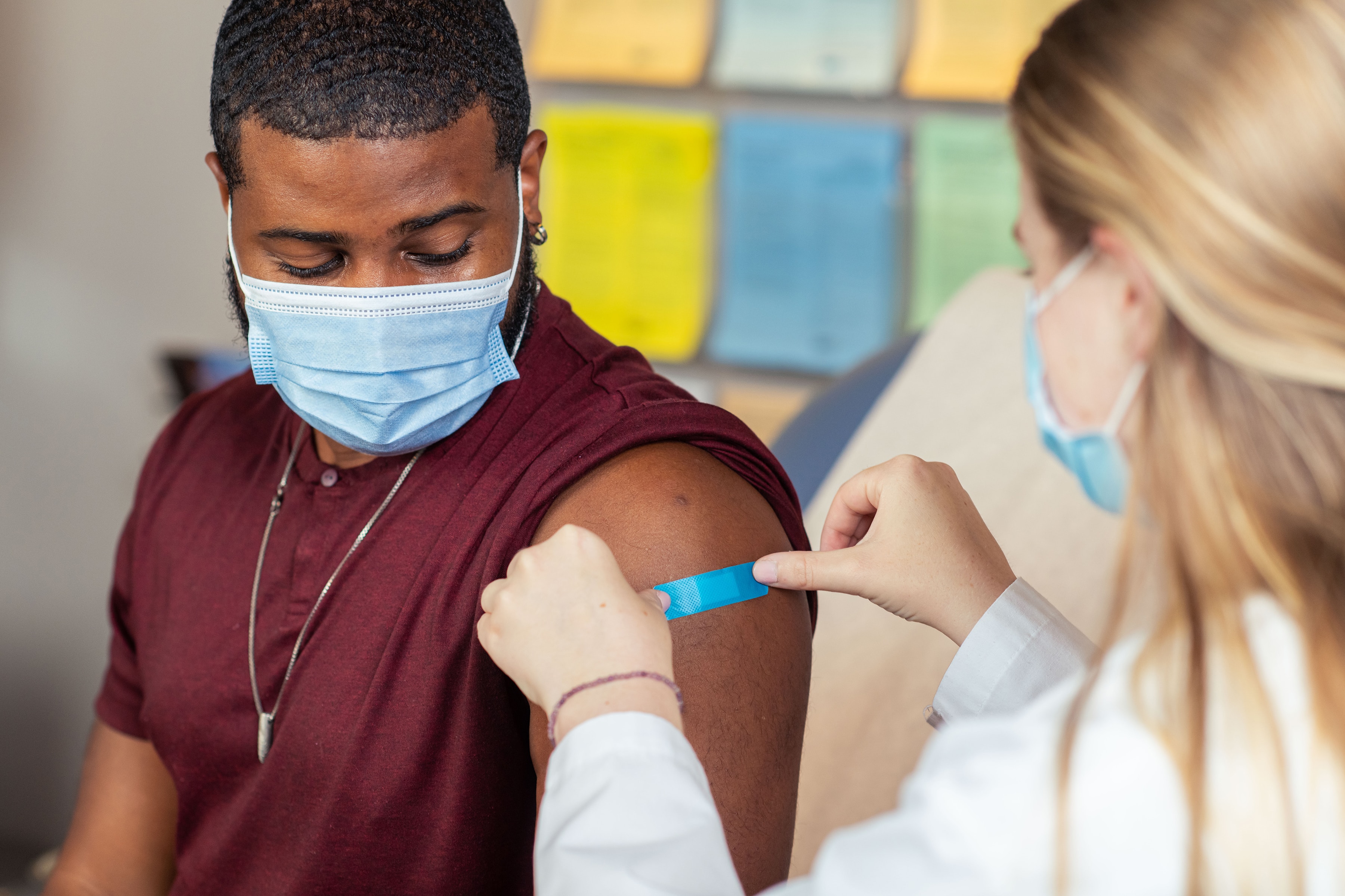 Medical provider placing a blue bandage on a patient's arm 